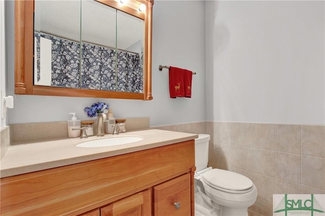 bathroom with vanity, tile walls, and toilet