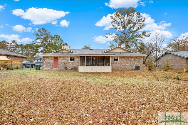 rear view of property featuring a lawn, a sunroom, and central air condition unit