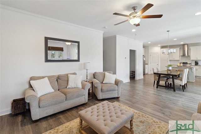 living room with hardwood / wood-style flooring, crown molding, and ceiling fan with notable chandelier