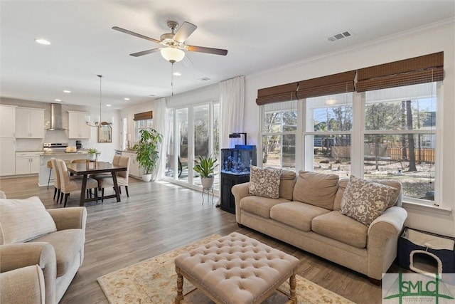 living room featuring crown molding, light hardwood / wood-style floors, and ceiling fan