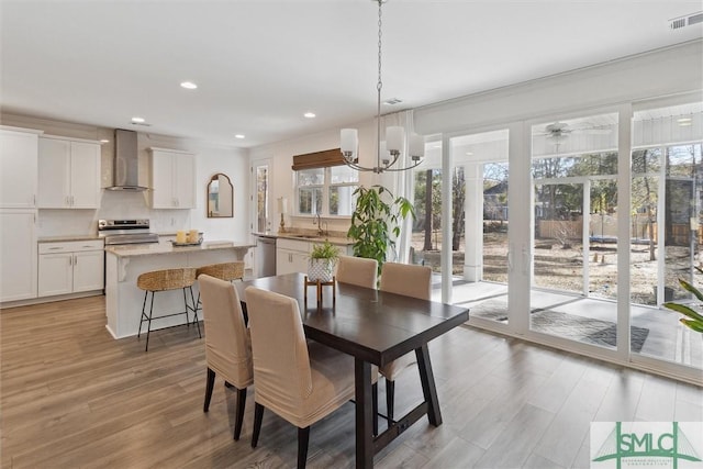 dining area featuring a notable chandelier, sink, and light wood-type flooring