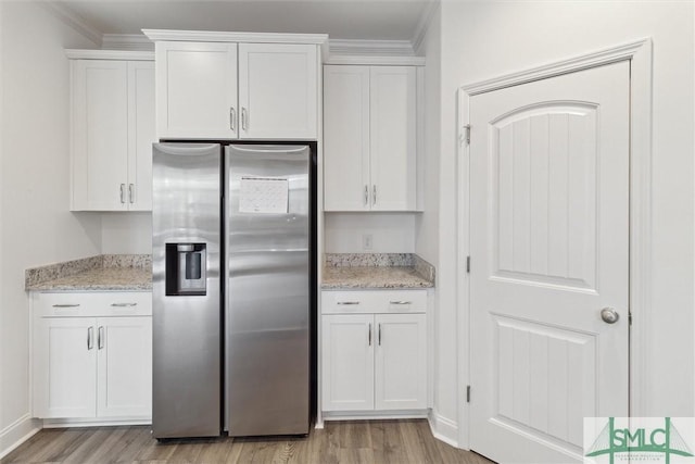 kitchen featuring light stone countertops, light hardwood / wood-style floors, white cabinets, and stainless steel refrigerator with ice dispenser