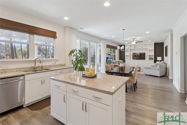 kitchen featuring sink, white cabinetry, a center island, dishwasher, and light stone countertops