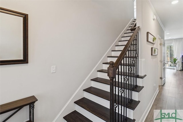 staircase featuring hardwood / wood-style floors and ornamental molding