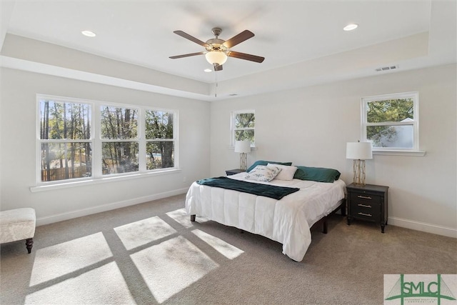 carpeted bedroom featuring ceiling fan and a raised ceiling