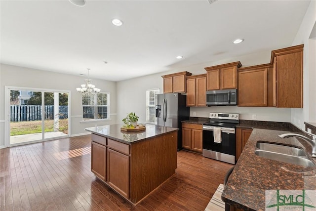 kitchen featuring sink, appliances with stainless steel finishes, hanging light fixtures, a kitchen island, and dark hardwood / wood-style flooring