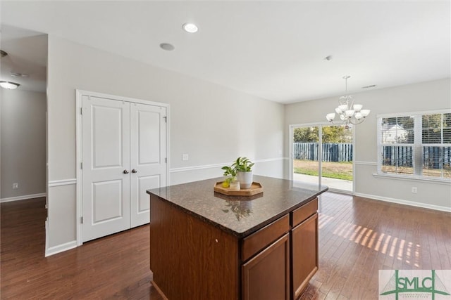 kitchen with dark hardwood / wood-style floors, decorative light fixtures, a center island, and an inviting chandelier