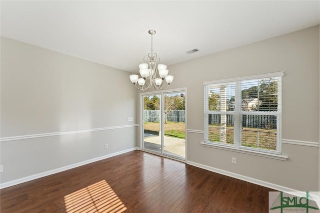 unfurnished dining area featuring dark hardwood / wood-style floors and a chandelier