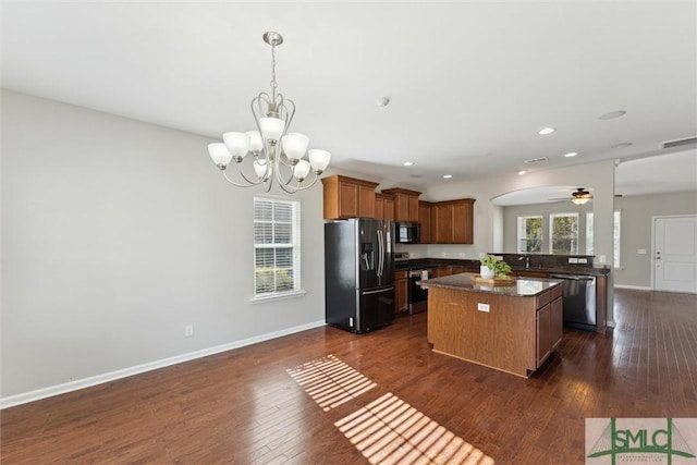 kitchen with stainless steel appliances, a healthy amount of sunlight, a center island, and dark wood-type flooring