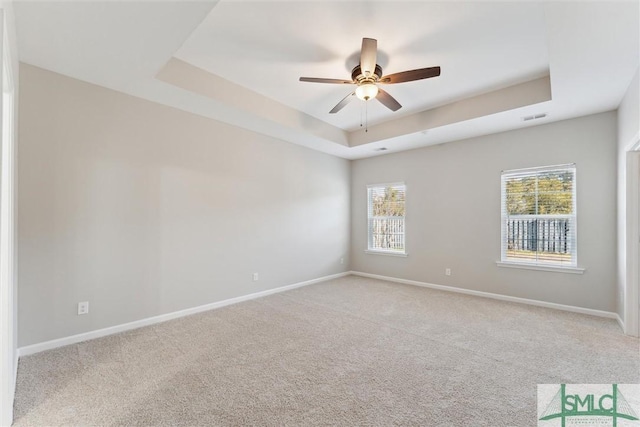 carpeted spare room with ceiling fan and a tray ceiling