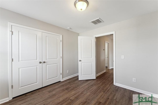 unfurnished bedroom with dark wood-type flooring and a closet