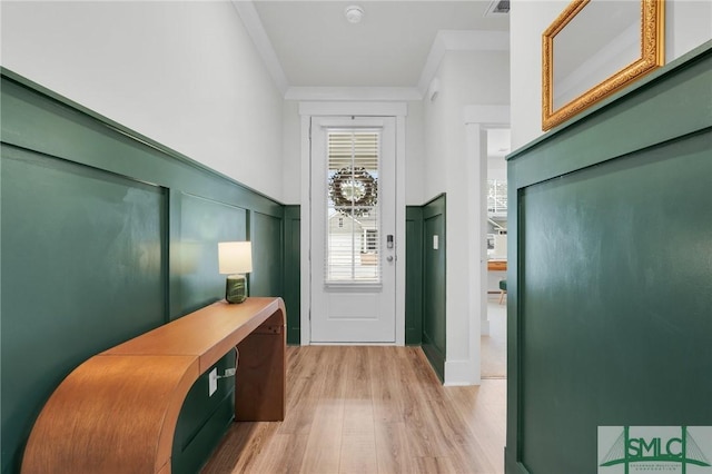 entrance foyer with ornamental molding and light hardwood / wood-style floors