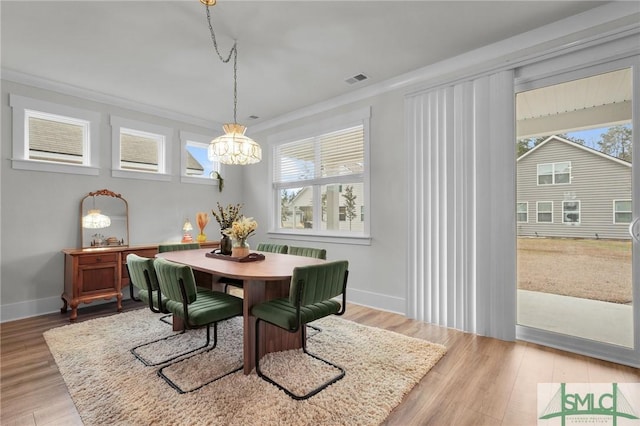 dining room with crown molding, a notable chandelier, wood finished floors, and a healthy amount of sunlight