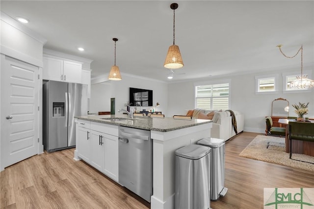 kitchen featuring light stone counters, ornamental molding, a sink, appliances with stainless steel finishes, and open floor plan