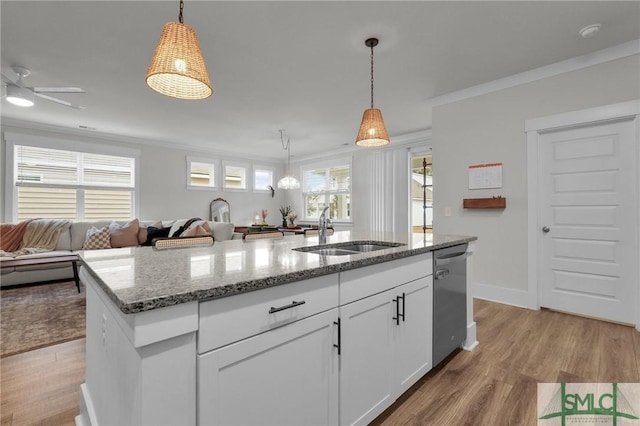 kitchen with light wood finished floors, a sink, stainless steel dishwasher, crown molding, and open floor plan