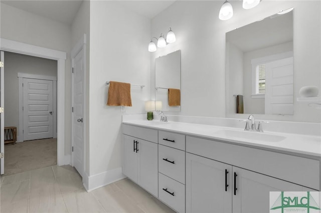 full bath with a sink, baseboards, and double vanity