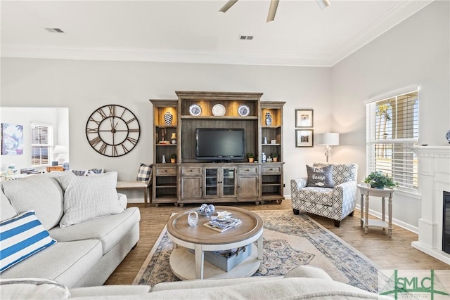 living room with wood-type flooring, ornamental molding, and ceiling fan