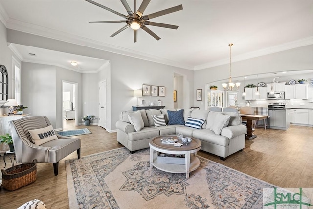 living room with wood-type flooring, ornamental molding, and a chandelier