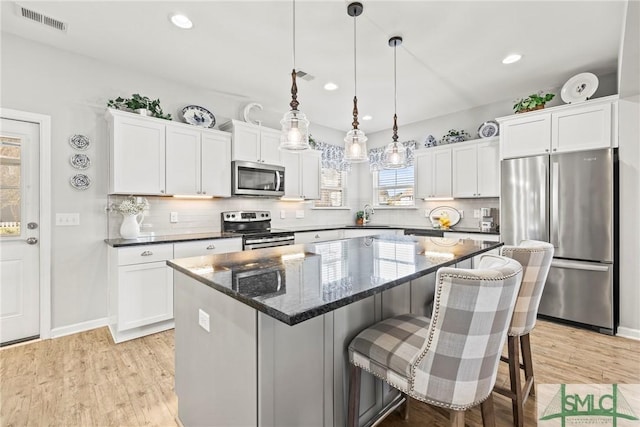 kitchen featuring pendant lighting, white cabinets, a center island, light hardwood / wood-style floors, and stainless steel appliances