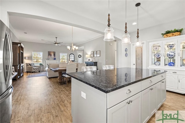 kitchen featuring a center island, light hardwood / wood-style flooring, hanging light fixtures, dark stone counters, and white cabinets