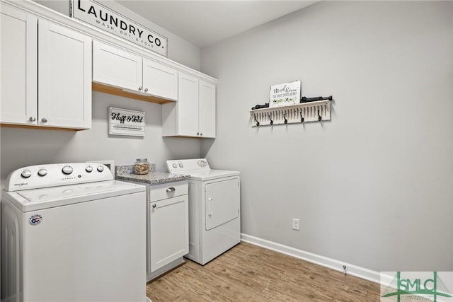 clothes washing area with separate washer and dryer, cabinets, and light wood-type flooring