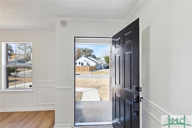 entryway featuring hardwood / wood-style flooring, ornamental molding, and a textured ceiling