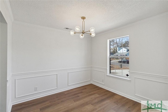 spare room featuring hardwood / wood-style flooring, ornamental molding, an inviting chandelier, and a textured ceiling