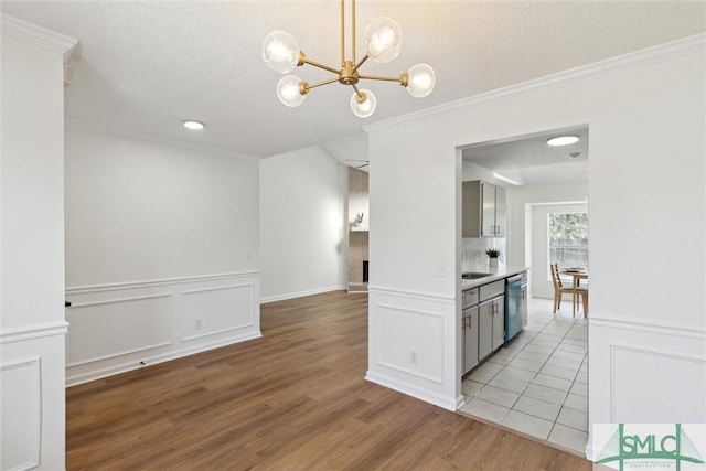 kitchen with crown molding, light hardwood / wood-style flooring, dishwasher, a notable chandelier, and a textured ceiling