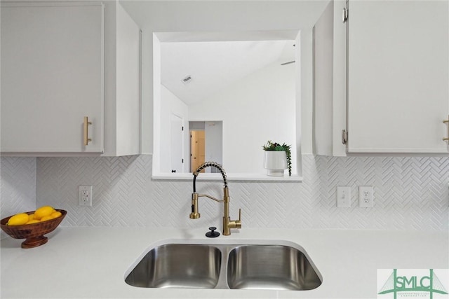 kitchen featuring white cabinetry, sink, decorative backsplash, and lofted ceiling