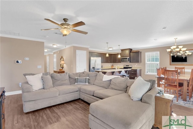 living room featuring ornamental molding, ceiling fan with notable chandelier, and dark hardwood / wood-style flooring