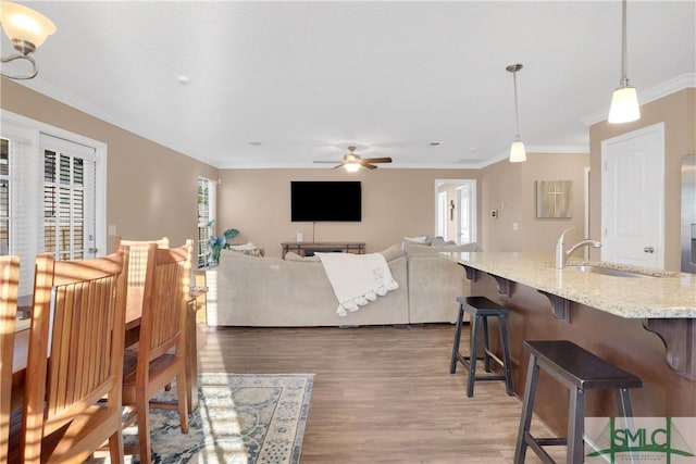 dining area with hardwood / wood-style flooring, ornamental molding, sink, and ceiling fan