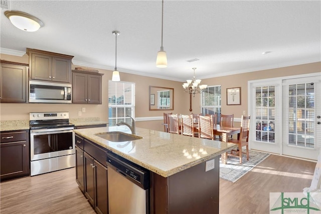 kitchen featuring dark brown cabinetry, sink, decorative light fixtures, an island with sink, and stainless steel appliances