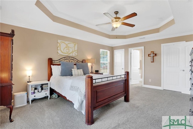 bedroom featuring crown molding, ceiling fan, a tray ceiling, and light carpet