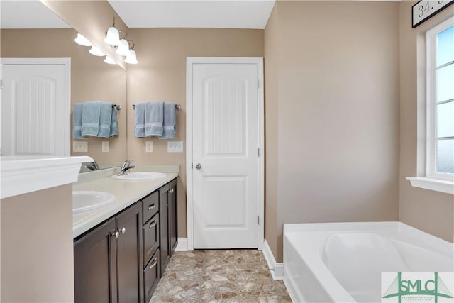 bathroom featuring vanity, a bathtub, and a healthy amount of sunlight