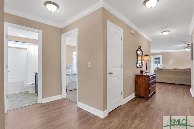 corridor with hardwood / wood-style flooring, ornamental molding, and a textured ceiling