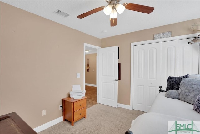 bedroom with light colored carpet, ceiling fan, and a closet