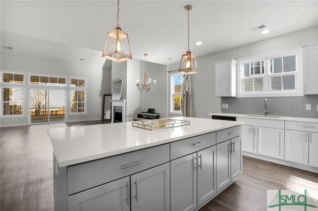 kitchen featuring sink, gray cabinetry, hanging light fixtures, dark hardwood / wood-style floors, and a kitchen island