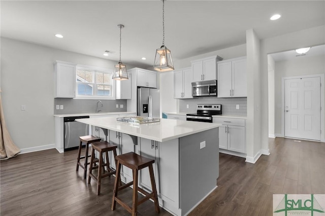 kitchen featuring white cabinetry, hanging light fixtures, a kitchen island, and appliances with stainless steel finishes