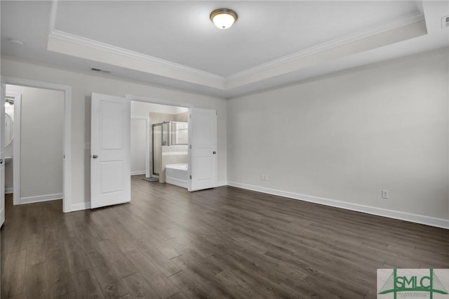 unfurnished bedroom with dark hardwood / wood-style flooring, ornamental molding, a raised ceiling, and ensuite bathroom