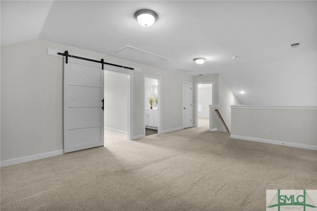 empty room with light carpet, lofted ceiling, and a barn door