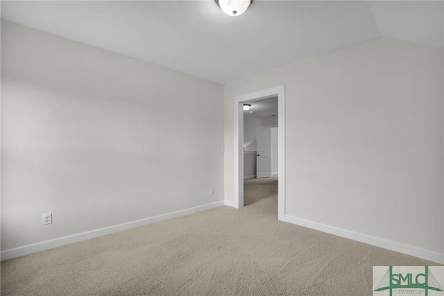 empty room featuring vaulted ceiling and light colored carpet