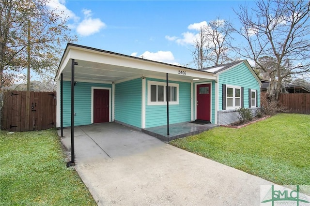 view of front of property with concrete driveway, a front lawn, fence, and an attached carport