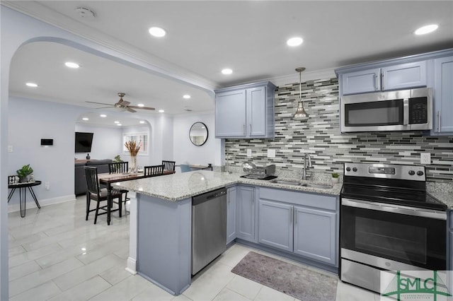 kitchen featuring pendant lighting, sink, appliances with stainless steel finishes, light stone counters, and kitchen peninsula