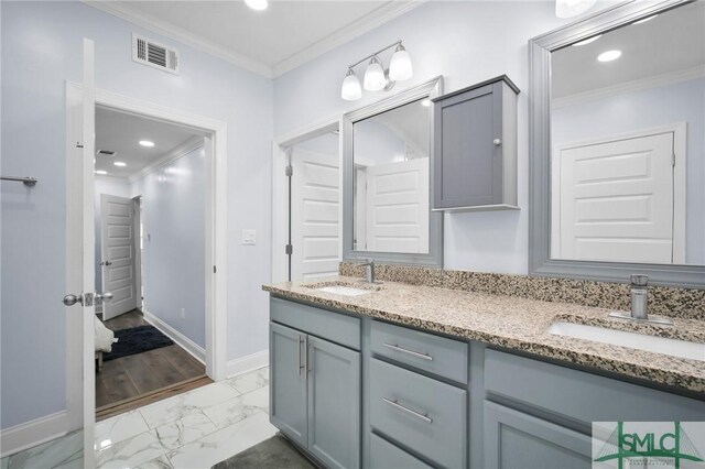 bathroom with marble finish floor, visible vents, a sink, and ornamental molding