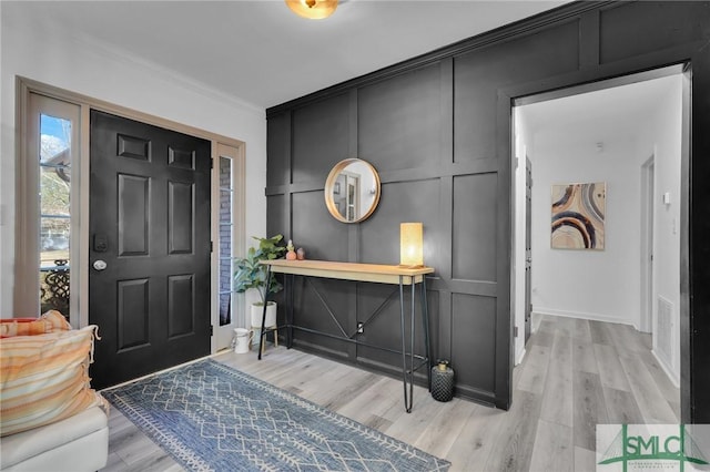 entryway with crown molding and light hardwood / wood-style floors