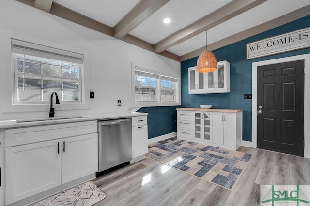 kitchen with beamed ceiling, white cabinetry, sink, hanging light fixtures, and stainless steel dishwasher