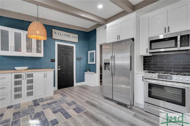 kitchen featuring white cabinetry, hanging light fixtures, light wood-type flooring, stainless steel appliances, and beam ceiling