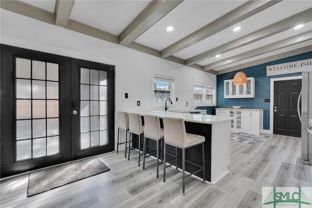 kitchen featuring a kitchen bar, kitchen peninsula, hanging light fixtures, and white cabinets