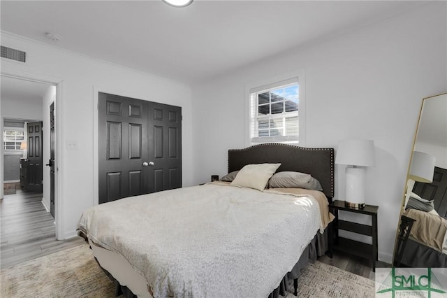 bedroom with light hardwood / wood-style floors and a closet