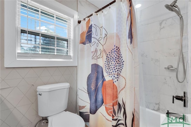 bathroom featuring toilet, shower / bath combo with shower curtain, and tile walls